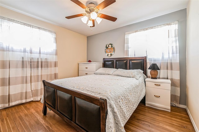 bedroom featuring baseboards, wood finished floors, and a ceiling fan