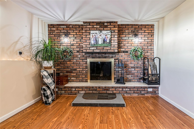 unfurnished living room featuring baseboards, wood finished floors, and a fireplace