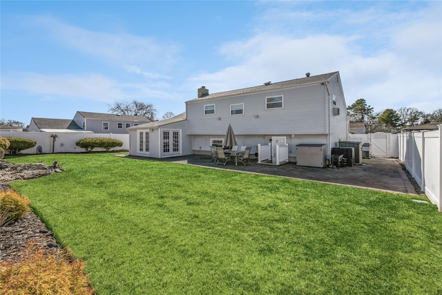 rear view of property with a patio, french doors, a fenced backyard, and a chimney