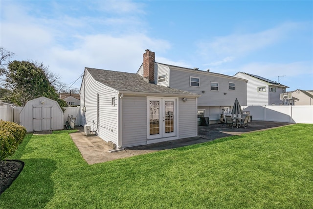 back of property with a chimney, a storage shed, a yard, a fenced backyard, and a patio area