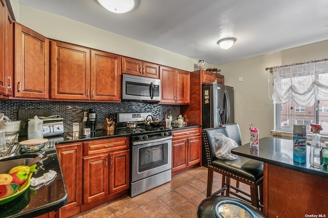 kitchen with decorative backsplash, a breakfast bar, light tile patterned floors, and stainless steel appliances