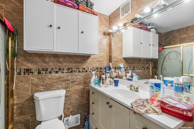 bathroom featuring toilet, vanity, and an enclosed shower