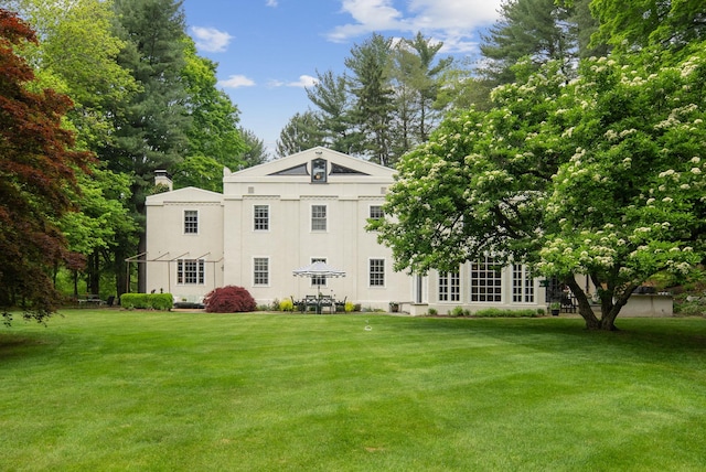 rear view of house featuring a yard and stucco siding