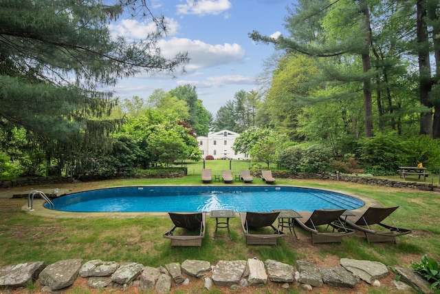 outdoor pool with a yard and view of scattered trees