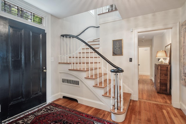 foyer featuring hardwood / wood-style floors, stairs, and baseboards
