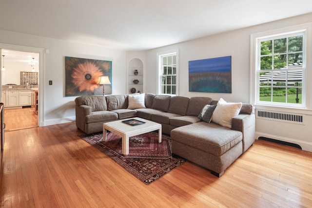 living area featuring light wood-style floors, built in features, and baseboards