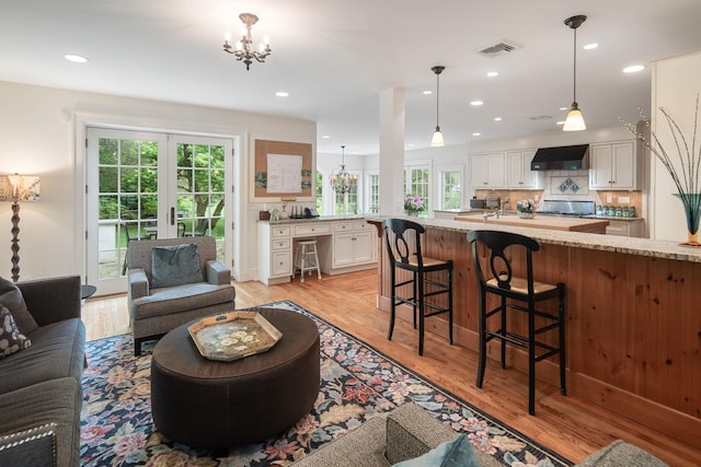 living area featuring a chandelier, healthy amount of natural light, light wood finished floors, and recessed lighting