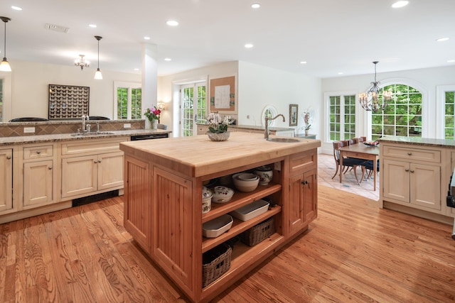 kitchen featuring a sink, butcher block countertops, light wood finished floors, a chandelier, and plenty of natural light