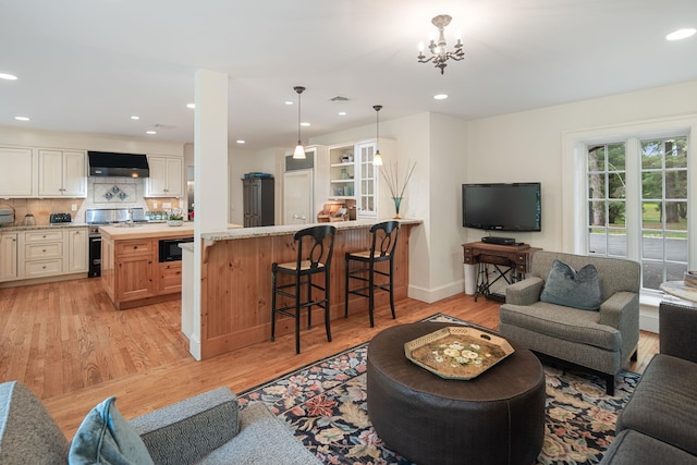 living area with light wood finished floors, recessed lighting, a chandelier, and baseboards