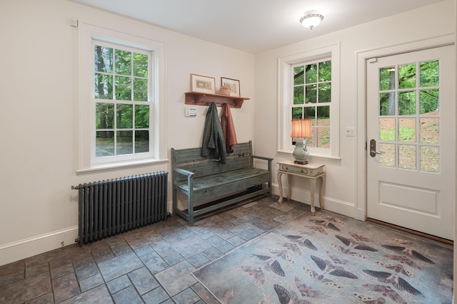 doorway featuring radiator, stone tile flooring, baseboards, and healthy amount of natural light