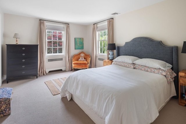 carpeted bedroom with multiple windows and radiator heating unit