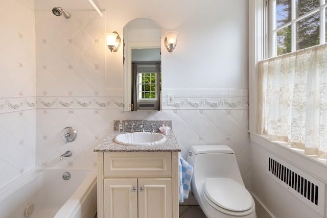 bathroom with radiator heating unit, toilet, vanity, bathing tub / shower combination, and tile walls