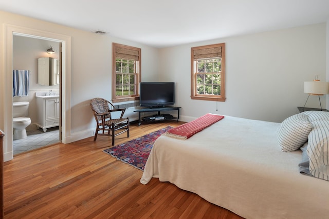 bedroom with light wood finished floors, multiple windows, and baseboards