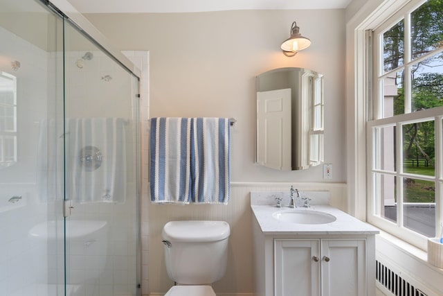 bathroom featuring radiator, toilet, wainscoting, a shower stall, and vanity
