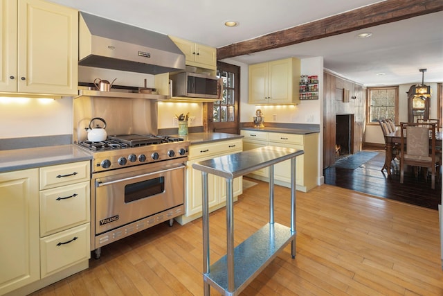 kitchen featuring decorative light fixtures, exhaust hood, stainless steel appliances, cream cabinets, and light wood-type flooring