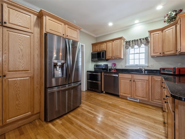 kitchen with sink, crown molding, light hardwood / wood-style flooring, stainless steel appliances, and dark stone counters