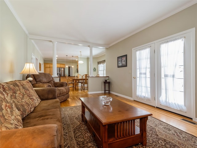 living room featuring crown molding, wood-type flooring, and decorative columns