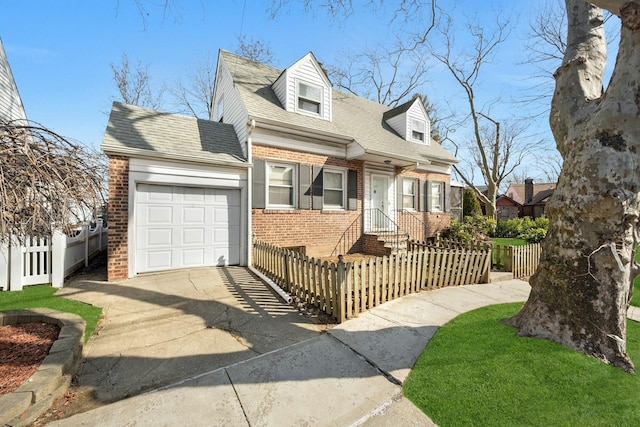 cape cod home featuring driveway, a garage, a fenced front yard, roof with shingles, and brick siding