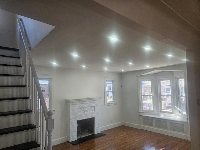 unfurnished living room featuring hardwood / wood-style floors, radiator, and a fireplace