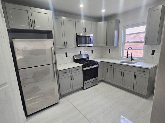 kitchen with backsplash, sink, gray cabinetry, and stainless steel appliances