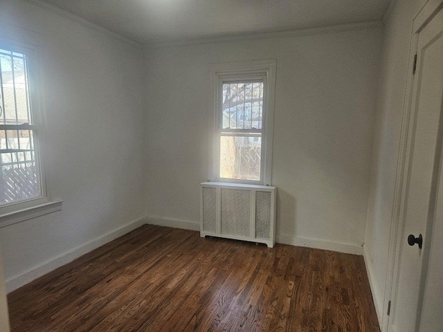 empty room featuring dark hardwood / wood-style flooring, radiator heating unit, and ornamental molding