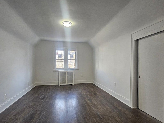 additional living space featuring dark wood-type flooring, radiator, and vaulted ceiling