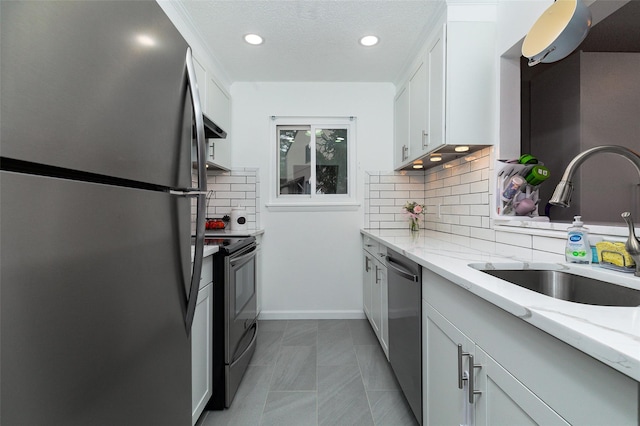 kitchen with light stone countertops, appliances with stainless steel finishes, white cabinets, and sink