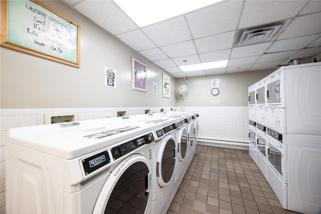 laundry room featuring stacked washing maching and dryer, separate washer and dryer, and dark tile patterned flooring