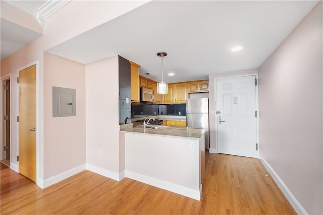 kitchen featuring light stone countertops, appliances with stainless steel finishes, light hardwood / wood-style floors, hanging light fixtures, and kitchen peninsula