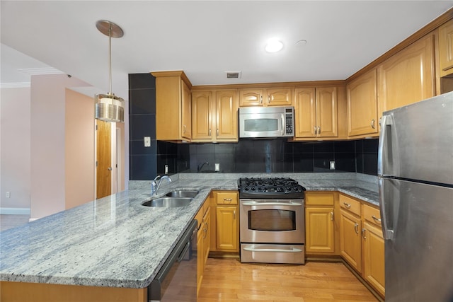 kitchen featuring pendant lighting, backsplash, light hardwood / wood-style flooring, and stainless steel appliances