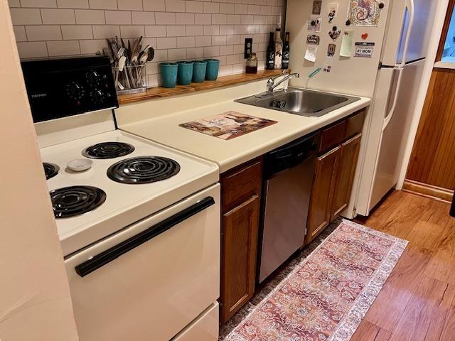 kitchen featuring sink, white appliances, tasteful backsplash, and light wood-type flooring