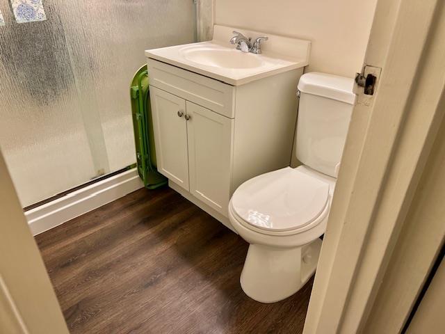 bathroom featuring toilet, hardwood / wood-style floors, an enclosed shower, and vanity