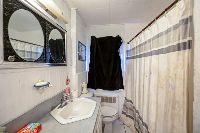 bathroom featuring toilet, vanity, tile patterned flooring, wood walls, and radiator