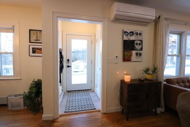 entryway featuring a wealth of natural light, hardwood / wood-style flooring, a baseboard radiator, and a wall unit AC