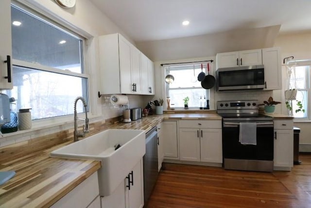 kitchen featuring dark wood-type flooring, appliances with stainless steel finishes, white cabinetry, and sink