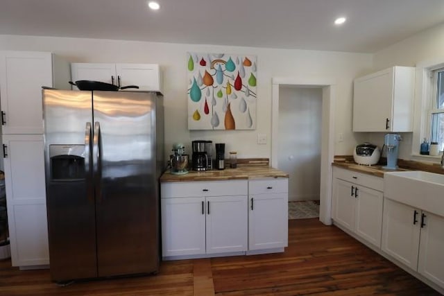 kitchen featuring stainless steel fridge with ice dispenser, wood counters, white cabinetry, and sink