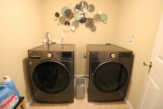 clothes washing area featuring light tile patterned flooring and washer and dryer