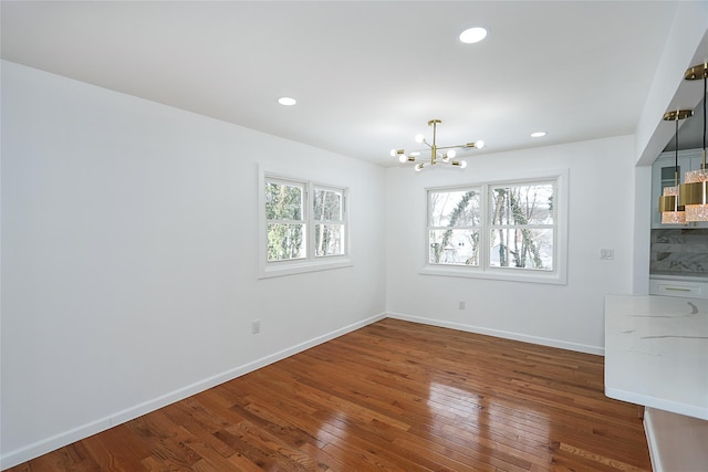 unfurnished dining area featuring an inviting chandelier and dark hardwood / wood-style flooring