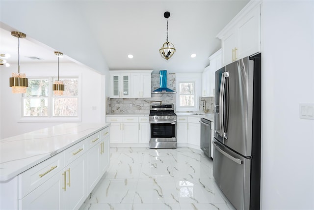 kitchen with appliances with stainless steel finishes, white cabinetry, and wall chimney range hood