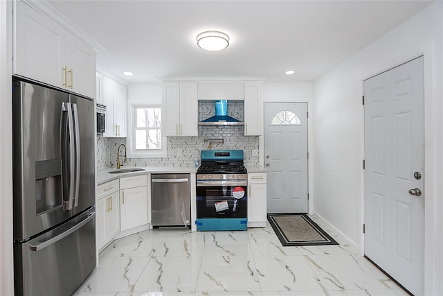 kitchen with stainless steel appliances, wall chimney exhaust hood, white cabinetry, and sink