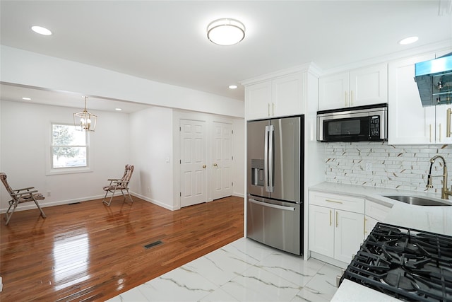 kitchen featuring appliances with stainless steel finishes, decorative backsplash, white cabinets, light stone counters, and sink