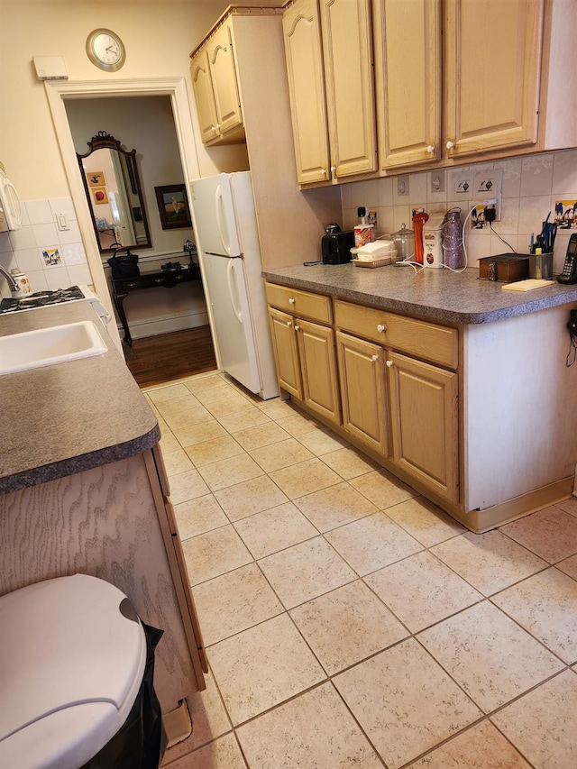 kitchen featuring light brown cabinets, white fridge, tasteful backsplash, sink, and light tile patterned floors