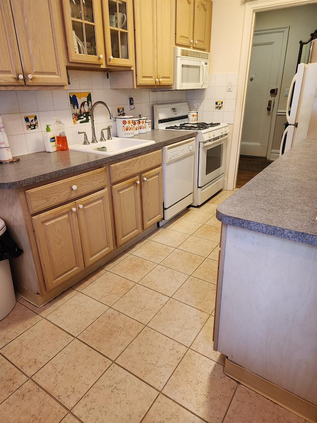 kitchen with tasteful backsplash, light tile patterned floors, sink, and white appliances