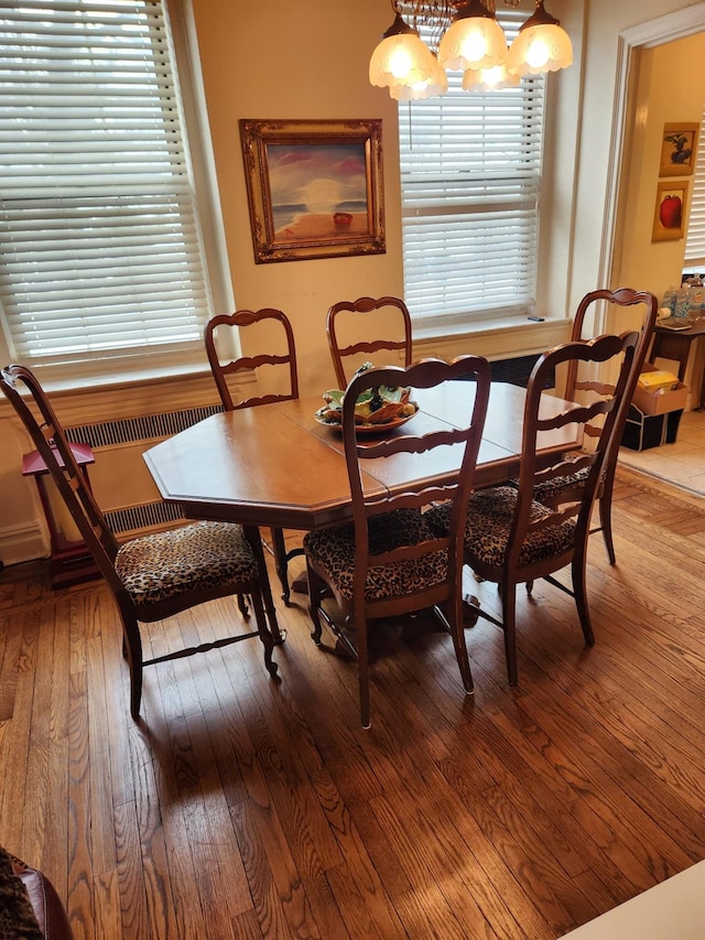 dining room featuring an inviting chandelier, radiator heating unit, and hardwood / wood-style floors