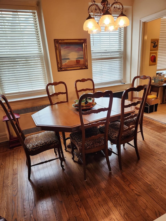 dining area featuring hardwood / wood-style flooring, radiator, and a chandelier