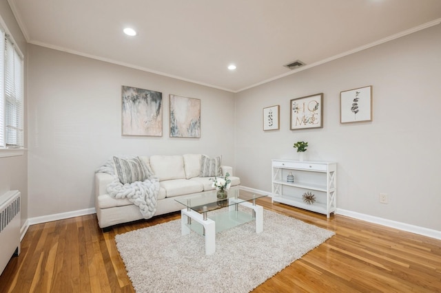 living room with wood-type flooring, radiator, and ornamental molding