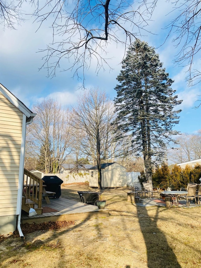 view of yard featuring a wooden deck and a storage shed