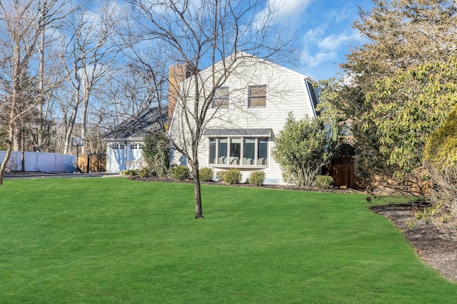 view of front of house featuring an attached garage, fence, a gambrel roof, and a front yard