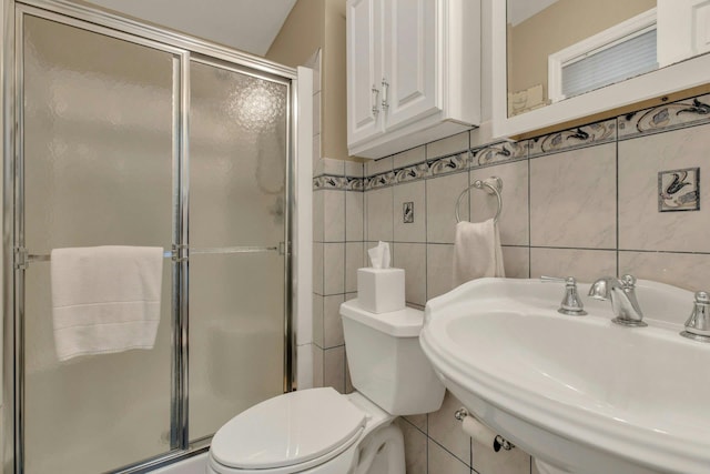 full bath with toilet, a stall shower, tile walls, and a sink