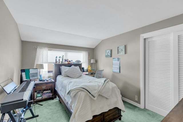 bedroom with a closet, light carpet, vaulted ceiling, and baseboards